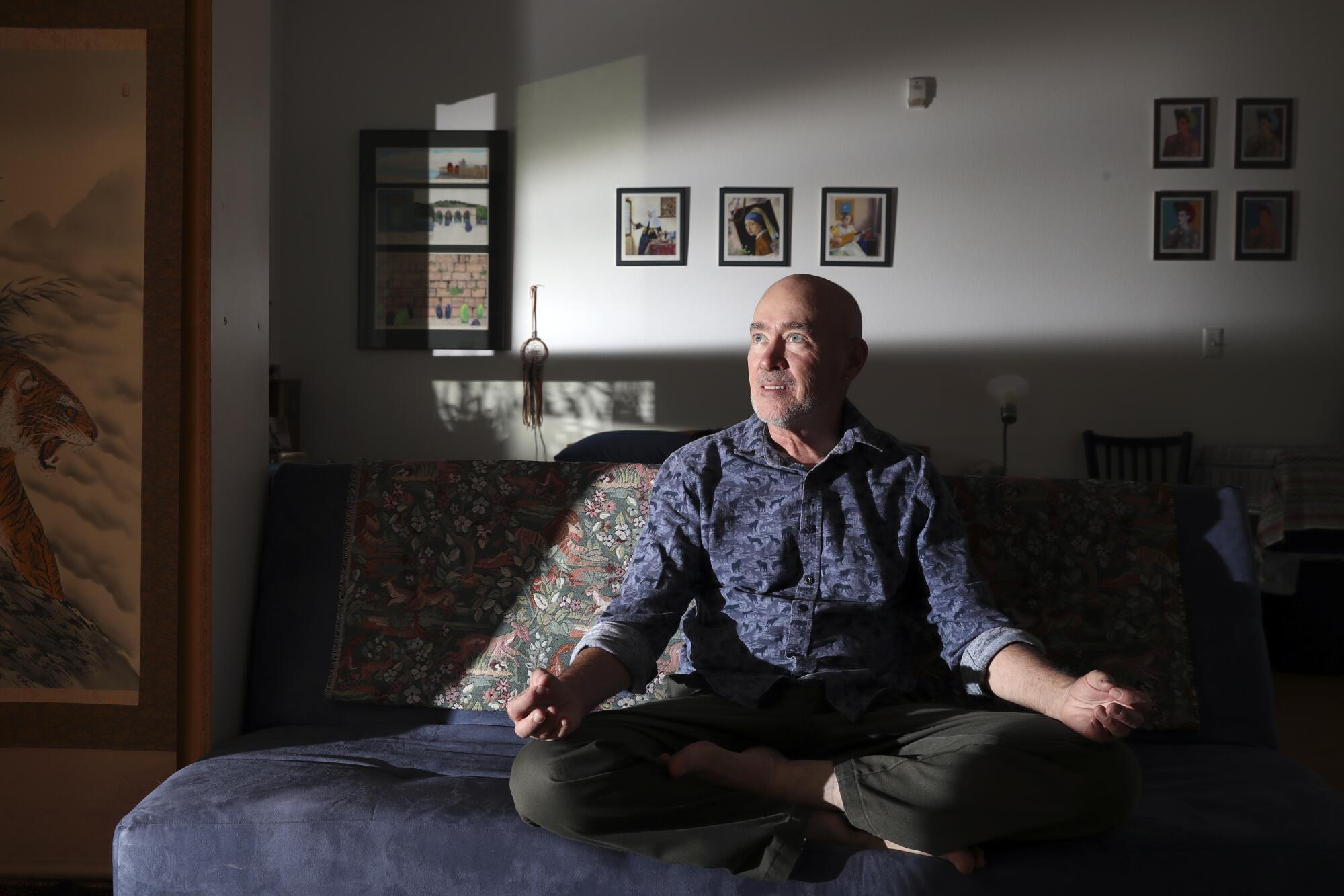  Terrance Whitten sits in a meditation pose on a sofa.