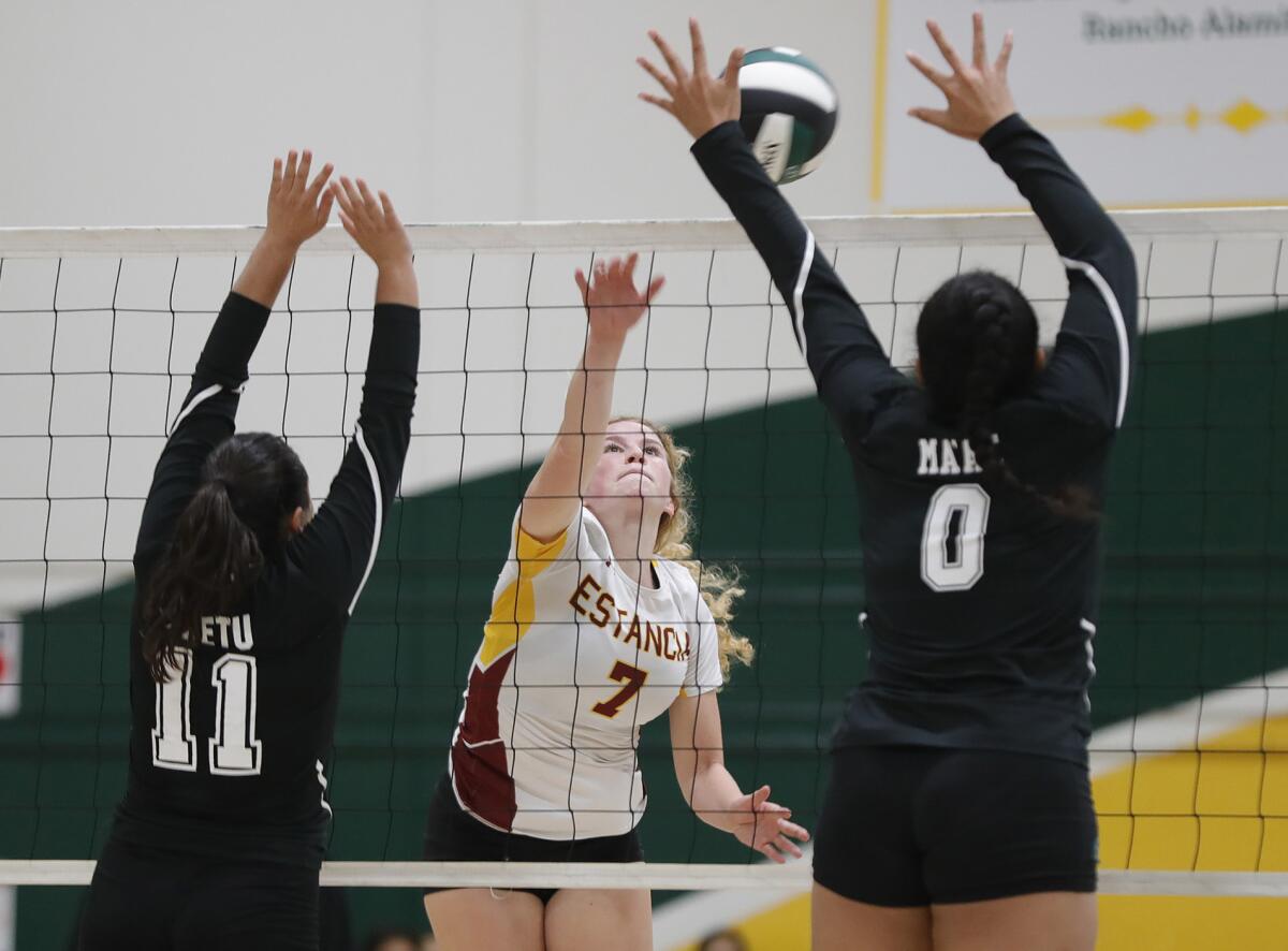 Estancia's Ruby Uchytil (7) kills the ball past two Rancho Alamitos blockers in a girls' volleyball match on Thursday.