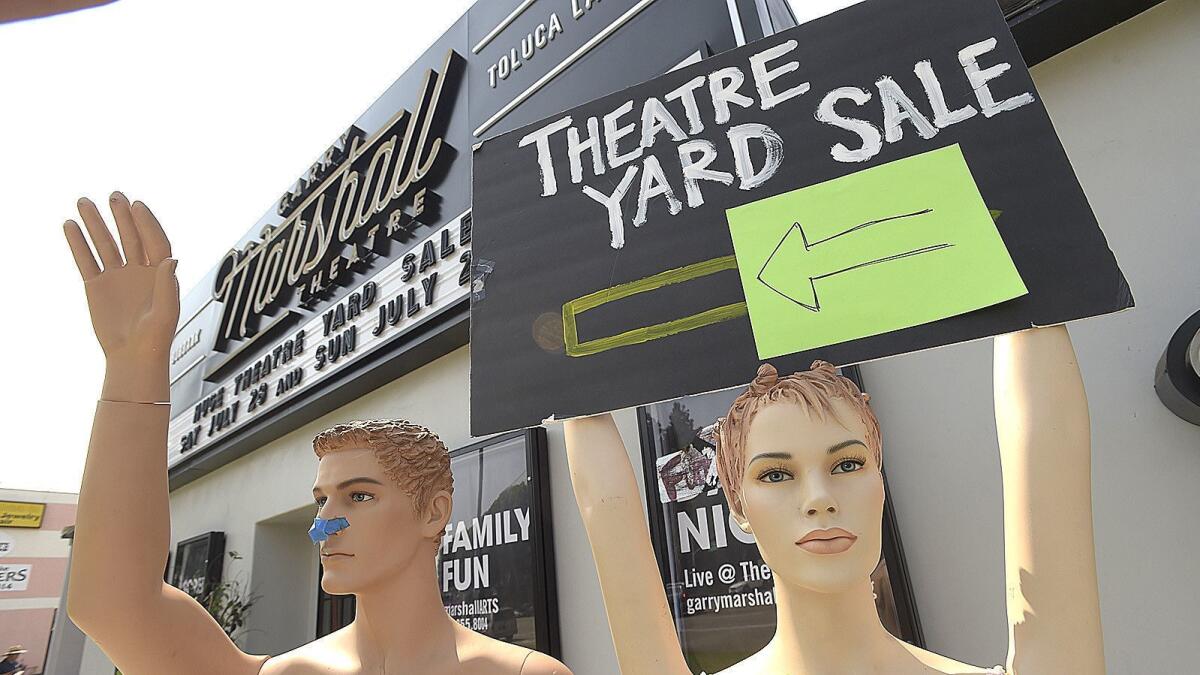 Two mannequins appear to wave to passing cars on Riverside Drive as they stand in front of the Garry Marshall Theatre to promote the weekend fundraising yard sale in Burbank on Saturday.
