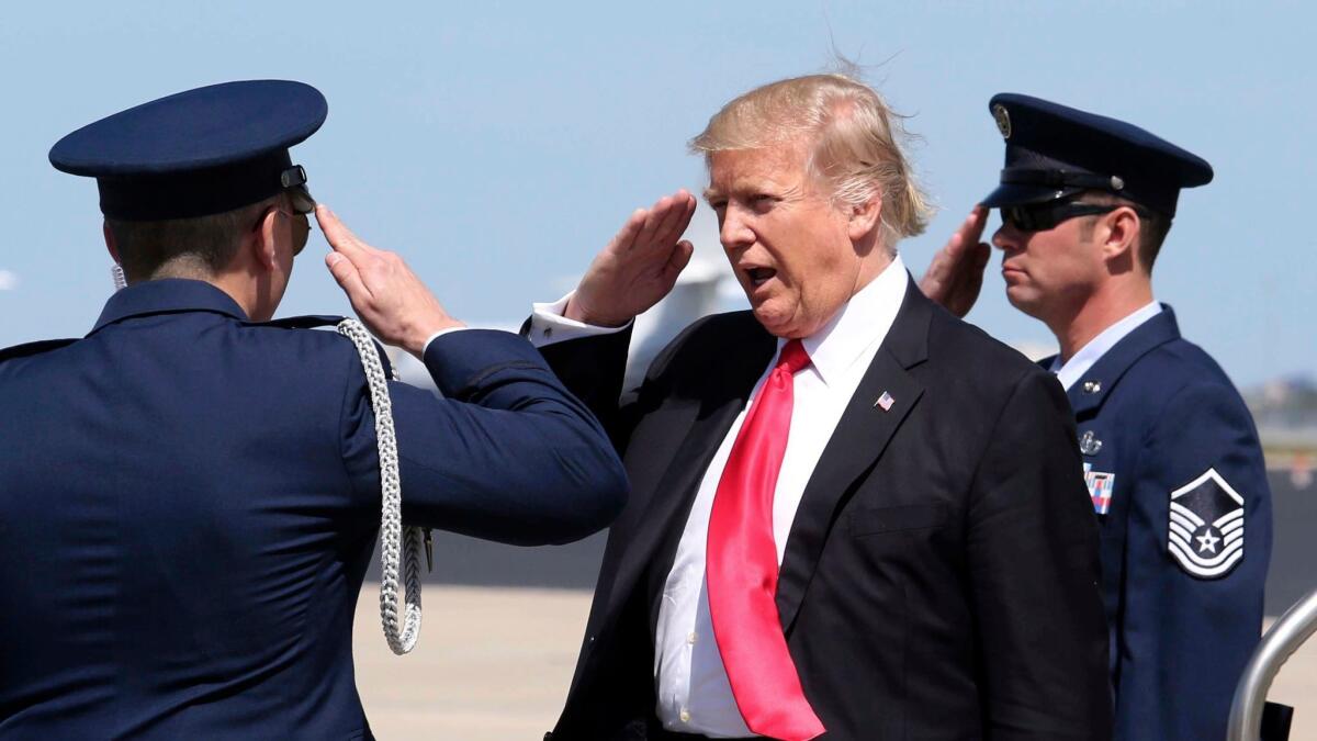 President Donald Trump, center, salutes the U.S. Air Force security detail at Orlando International Airport on March 3.