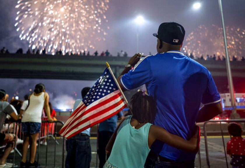FILE - In this July 4, 2018 file photo, Deon Stewart and his daughter Semiyah, of New York, join other spectators as they watch a fireworks display on the east side of Manhattan, part of Independence Day festivities in New York. The Macy's Fourth of July fireworks show will return to New York City this year. (AP Photo/Craig Ruttle, File)