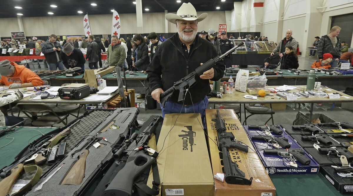 Ken Haiterman, of Pioneer Market, holds a CMMG 5.56mm AR 15 during the 2013 Rocky Mountain Gun Show in Sandy, Utah.