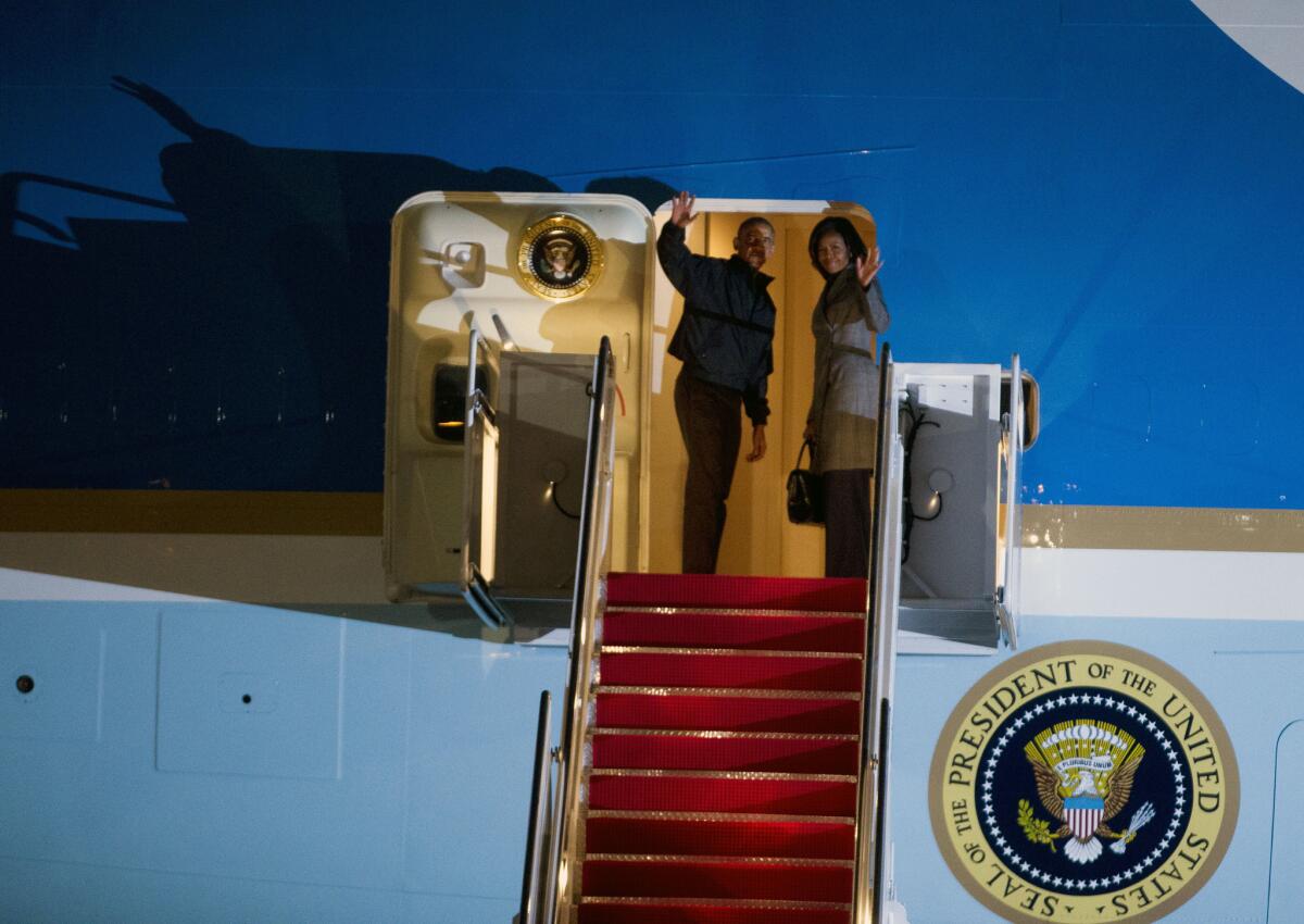 President Barack Obama and first lady Michelle Obama wave from Air Force One at Andrews Air Force Base, Md., before leaving for India.