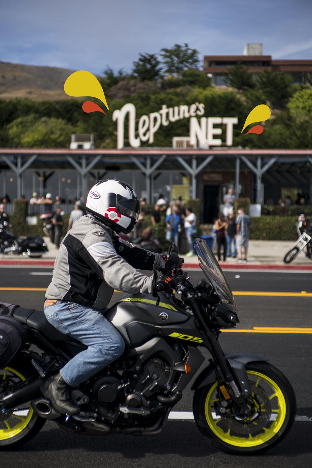 A motorcyclist rides along the Pacific Coast Highway in front of Neptune's Net in Malibu, Calif.