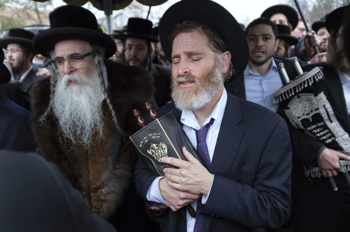 Rabbi Chaim Rottenberg, left, and others celebrate the arrival of a new Torah on Sunday. A day earlier, multiple people were stabbed in his home.