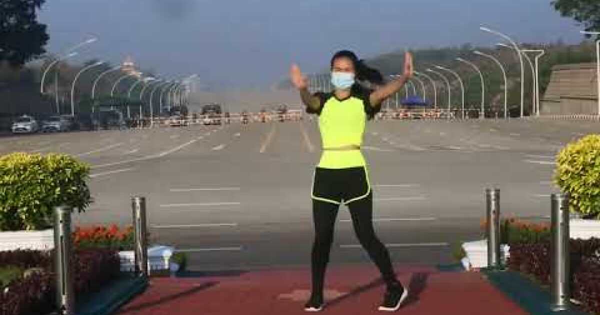 An aerobics instructor in Myanmar does her workout routine as a coup unfolds behind her