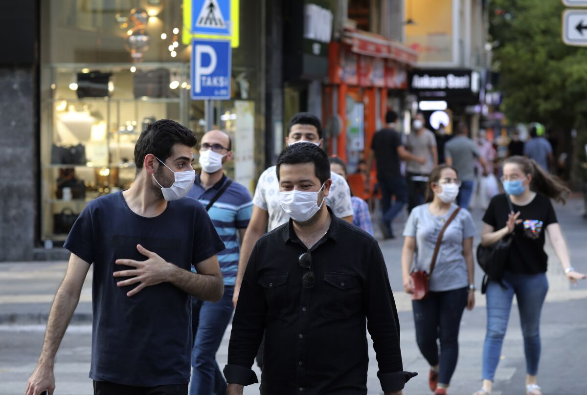 People wearing face masks to protect against the spread of coronavirus, walk in Ankara, Turkey, Thursday, Aug. 6, 2020. Turkey's interior ministry announced new measures Wednesday to curb the spread of COVID-19 as daily confirmed cases peaked above 1,000. (AP Photo/Burhan Ozbilici)
