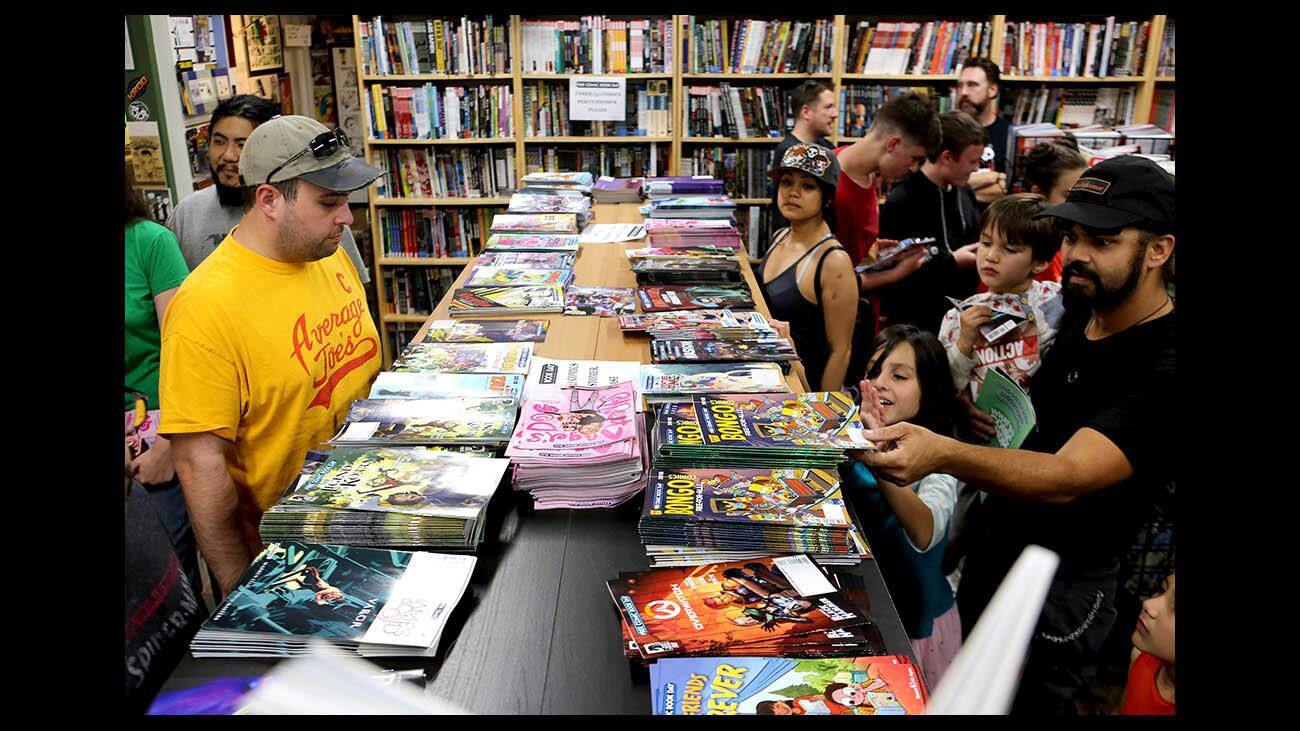 Customers look over free comics at House of Secrets Comics & Toys, on Free Comic Book Day, in Burbank, on Saturday, May 5, 2018.