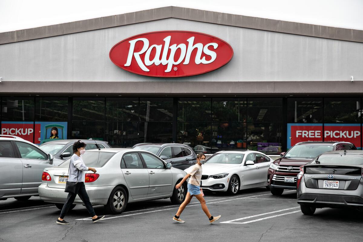 Cars and people walking in front of a Ralphs storefront.