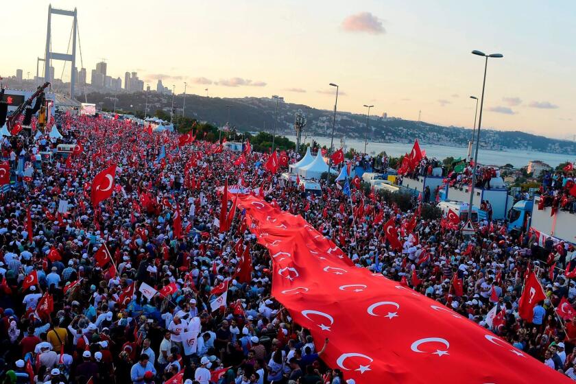 People stand under a collection of Turkish national flags as they gather on the "July 15 Martyrs Bridge" (Bosphorus Bridge) in Istanbul on July 15, 2017. Turkey is marking one year since the defeat of the coup aimed at ousting President Recep Tayyip Erdogan, seeking to showcase national unity and his grip on power in an increasingly polarised society. The authorities have declared July 15, a annual national holiday of "democracy and unity", billing the foiling of the putsch as a historic victory of Turkish democracy. / AFP PHOTO / YASIN AKGULYASIN AKGUL/AFP/Getty Images ** OUTS - ELSENT, FPG, CM - OUTS * NM, PH, VA if sourced by CT, LA or MoD **