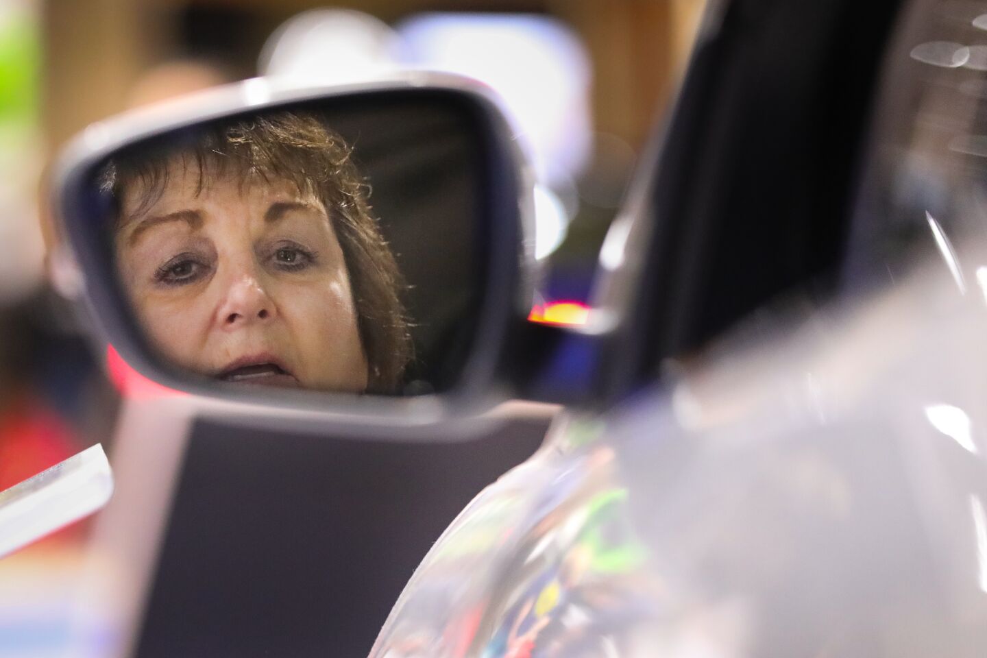 Edna Connolly of Carmel Mountain Ranch, looks in the side view mirror of a 2020 Ford Escape Titanium AWD SUV during the 2020 San Diego International Auto Show at the San Diego Convention Center, January 4, 2020.
