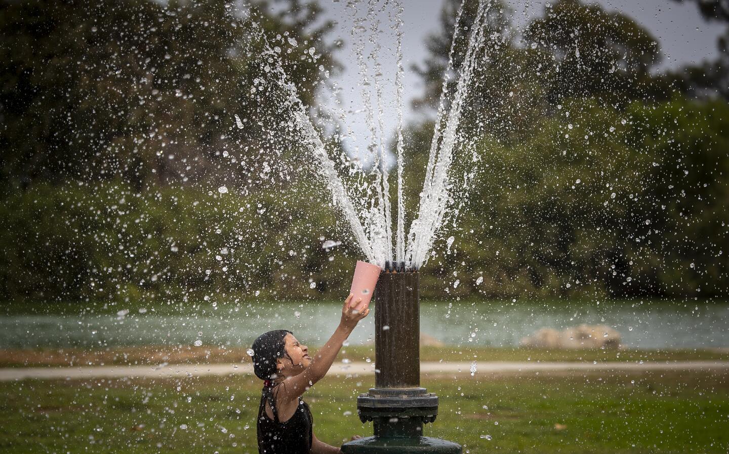 Laura Martinez, 8, plays in spray pool to cool off as hundreds of people spread out over Mile Square Park.