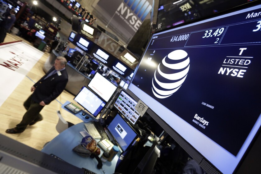 A trader walks by the post that handles AT&T on the floor of the New York Stock Exchange on March 6.