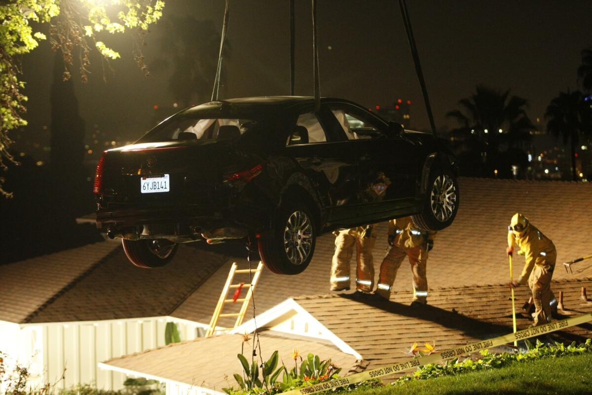 Crews remove a Cadillac from the roof of a house in Glendale Saturday night using a crane.