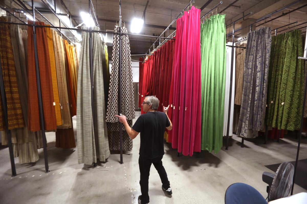 A man stands in front of a towering collection of colorful drapery.