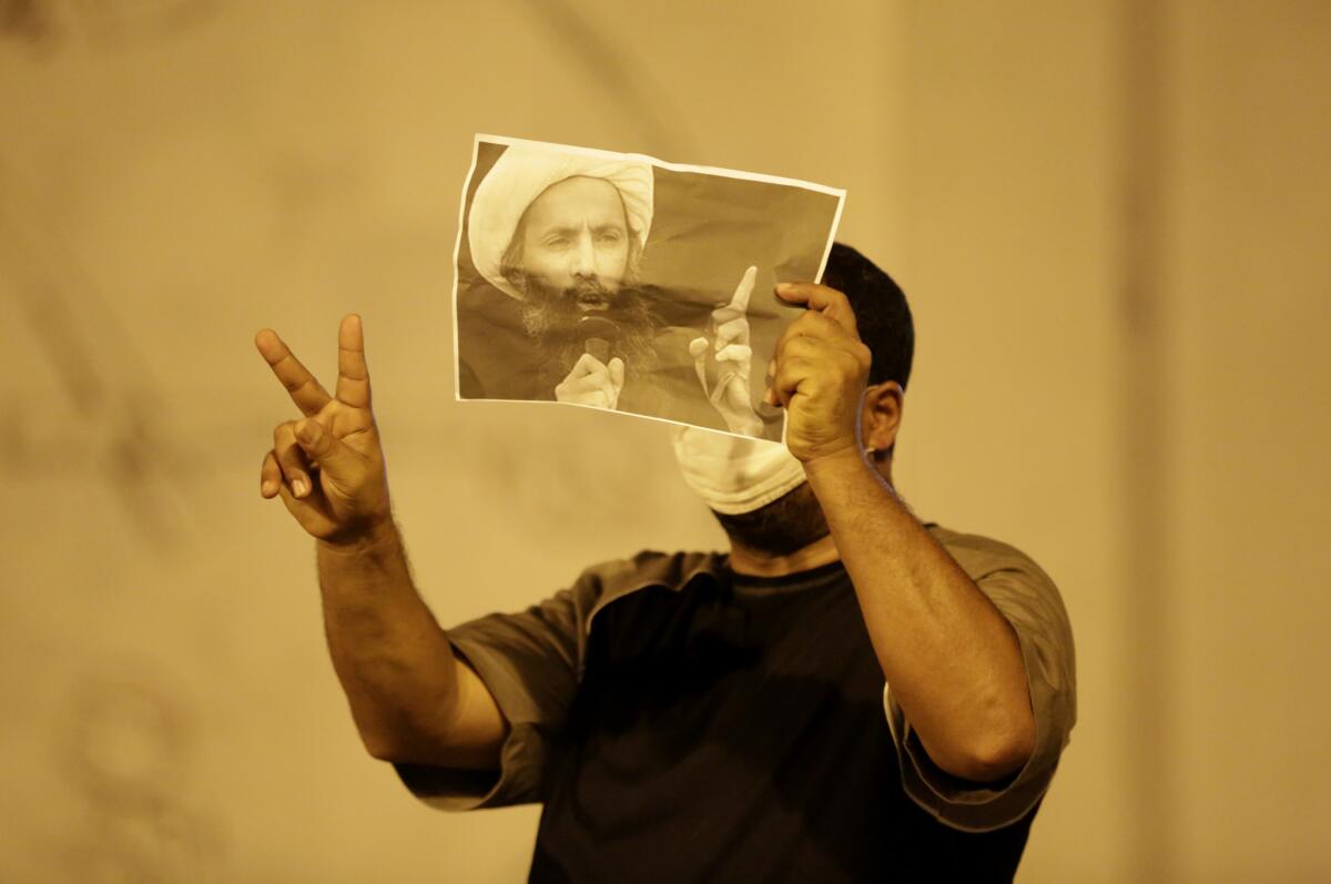 A Bahraini anti-government protester, masked against tear gas, holds up a picture of jailed Saudi Shiite Muslim cleric Sheik Nimr Baqir al Nimr during clashes with police in Sanabis, Bahrain. Saudi Arabia has sentenced Nimr to death.