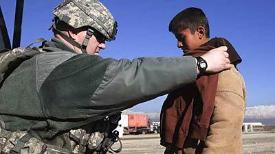 U.S. soldier Mike Greenberger checks the size of a shirt on an Afghan boy while distributing clothes on Thanksgiving Day in Bagram, north of Kabul, Afghanistan.