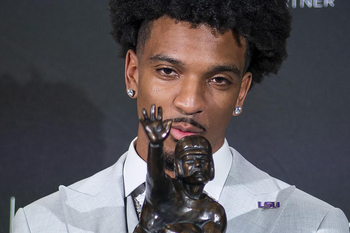 LSU quarterback Jayden Daniels kisses the Heisman Trophy during a news conference after winning the college football award.