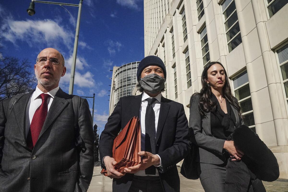 Roger Ng, al centro, un exbanquero de Goldman Sachs, sale de una corte federal 
