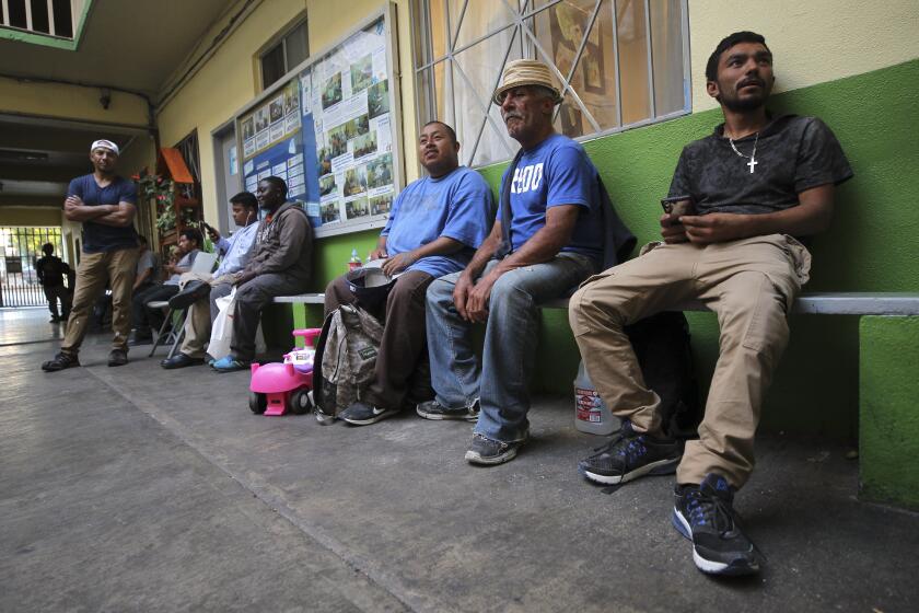 Men sit in the courtyard at Casa del Migrante, a shelter for migrants, asylum seekers, and deportees, on Friday, August 16, 2019 in Tijuana, Mexico.