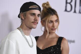 Justin Bieber and Hailey Baldwin pose together in front of a while backdrop