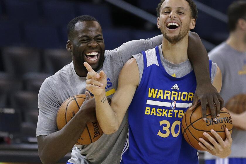 Warriors forward Draymond Green and guard Stephen Curry (30) share a laugh during practice Wednesday in Oakland.