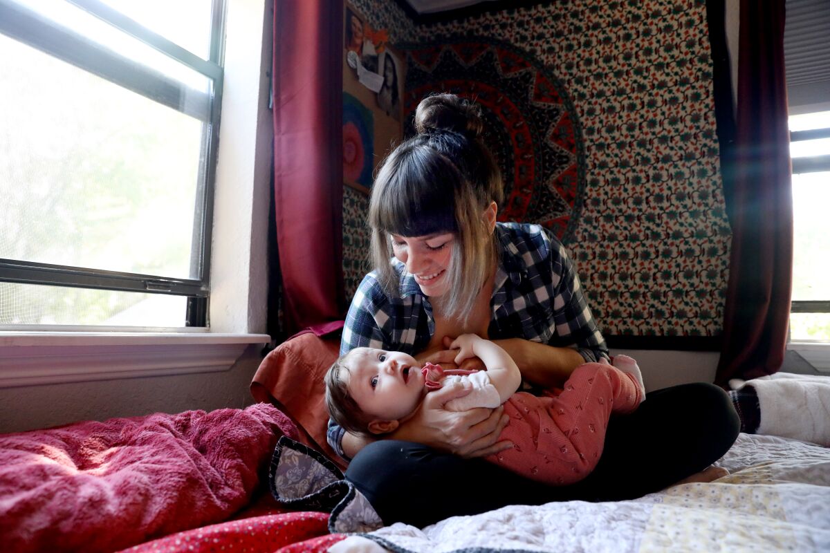 A woman with a baby on a bed.