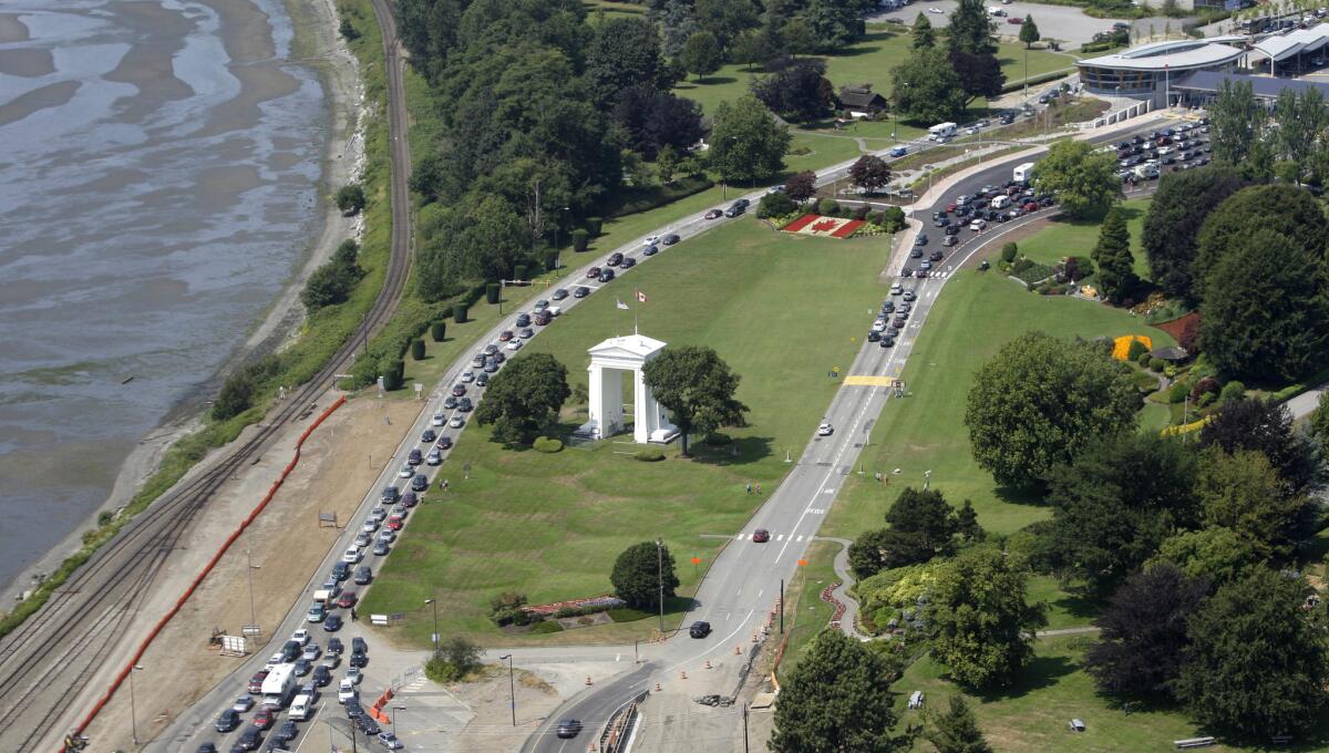 ARCHIVO - En esta fotografía de archivo del 24 de julio de 2009, varios vehículos hacen fila para cruzar hacia Estados Unidos, a la izquierda, y a Canadá, a la derecha, en la localidad canadiense de Boundary Bay, frente a Blaine, Washington. (AP Foto/Elaine Thompson)