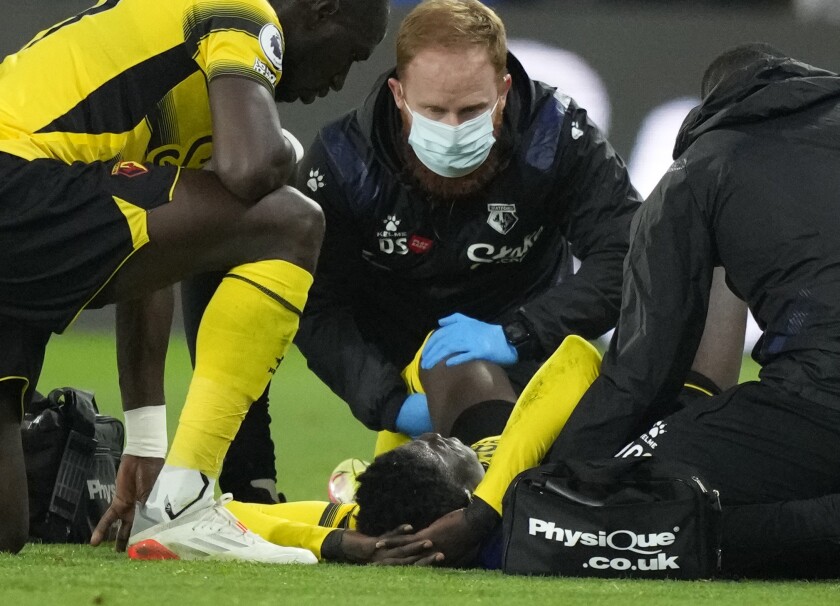 Watford's Ismaila Sarr receives medical treatment during the English Premier League soccer match between Watford and Manchester United at Vicarage Road, Watford, England, Saturday, Nov. 20, 2021. (AP Photo/Frank Augstein)