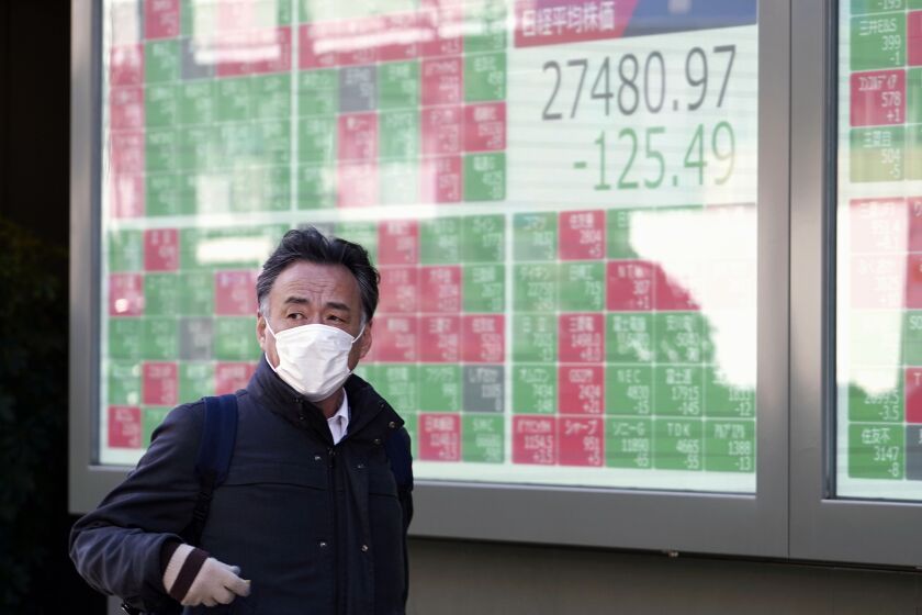 A person walks in front of an electronic stock board showing Japan's Nikkei 225 index at a securities firm Thursday, Feb. 9, 2023, in Tokyo. Shares fell Thursday in Asia after Wall Street gave back some of its recent gains on persisting uncertainty over interest rates and inflation. (AP Photo/Eugene Hoshiko)
