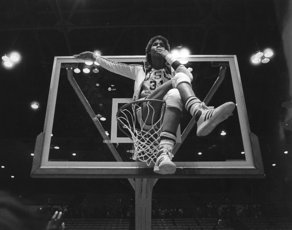 Cheryl Miller sits on top of the basketball hoop after the USC women's basketball defeated Louisiana Tech in the 1983 NCAA women's national basketball championship. 