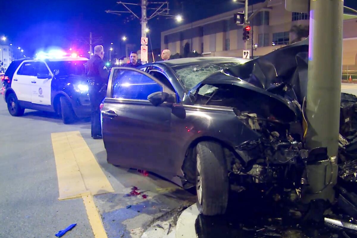 A car that crashed into a pole in Los Angeles early Sunday is blocked by a police vehicle. 