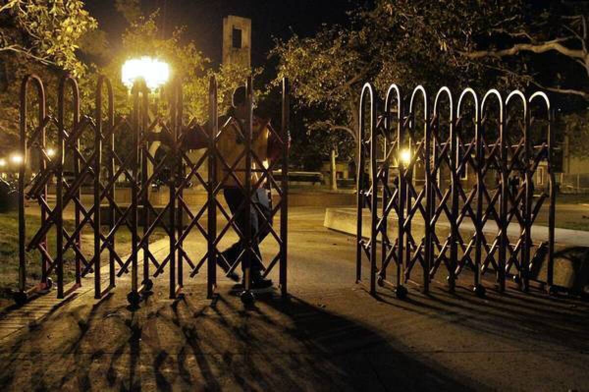 A guard closes a portable gate at USC under the new security precautions.
