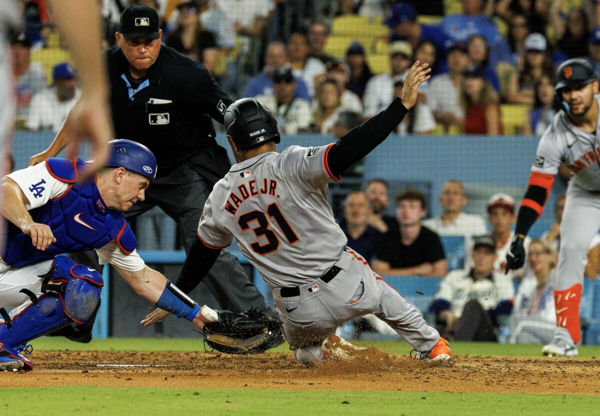 Giants first baseman LaMonte Wade Jr. slides around a tag attempt by Dodgers catcher Will Smith in the eighth inning