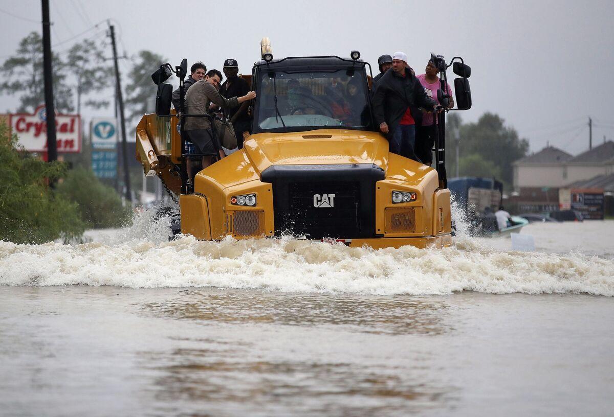 People catch a ride on a construction vehicle down a flooded Houston street. (Joe Raedle / Getty Images)
