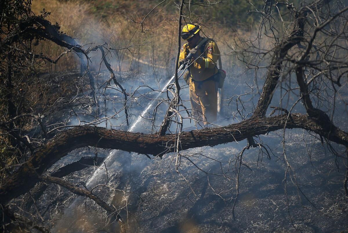A firefighter sprays water on a hot spot while battling the Wragg fire Thursday near Winters in Yolo County.