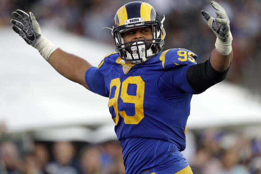 FILE - In this Nov. 11, 2018, file photo, Los Angeles Rams defensive end Aaron Donald celebrates a fumble recovery and touchdown by defensive end Dante Fowler during the second half in an NFL football game against the Seattle Seahawk, in Los Angeles. The roar of the crowd has been a staple of major sports and an advantage to the home team. When the virus risk wanes enough to allow the games to begin again, the very essence of these events will likely be missing for awhile. (AP Photo/Alex Gallardo, File)