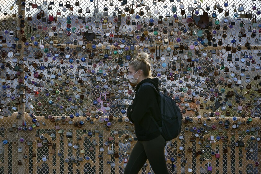 Locks cover the fence on the Love Bridge in the Oakland neighborhood of Pittsburgh as a person walks by Nov. 3, 2021. 