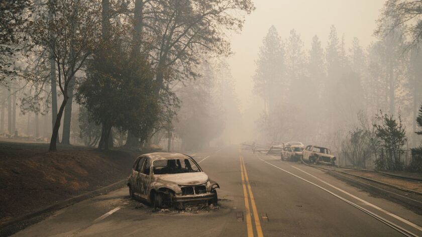 Charred vehicles are abandoned on a road in Paradise, Calif.