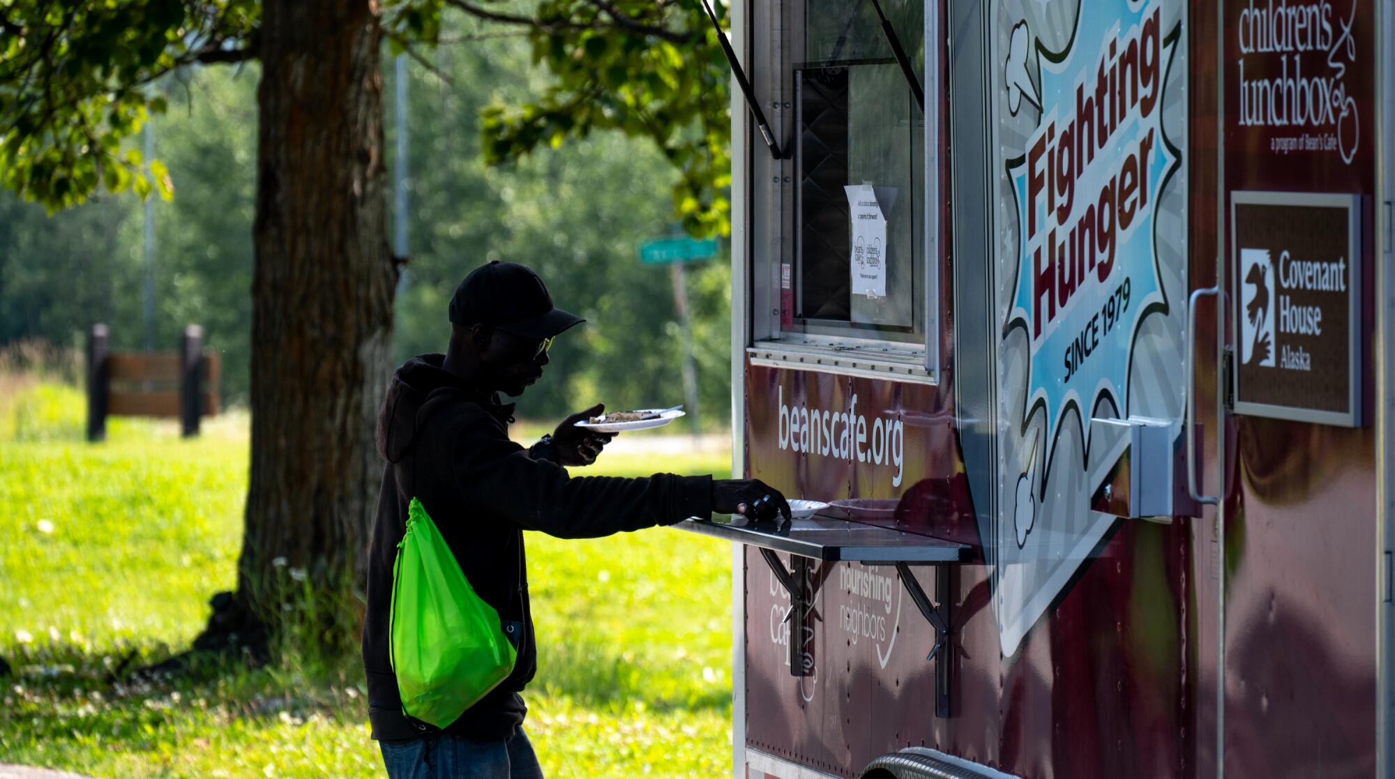 A man holds a plate as he stands near a food truck. 