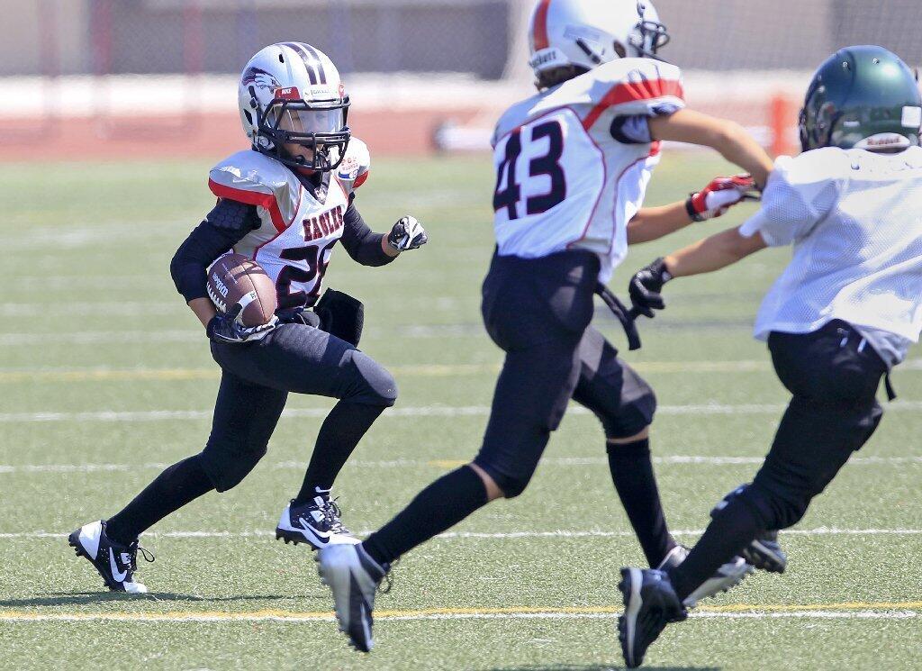 Josiah Lamarque, left, carries the ball for the Costa Mesa Pop Warner Eagles as teammate Parker Awad, center, blocks for him during a Mighty Mites Division scrimmage against Upland at Jim Scott Stadium on Saturday.
