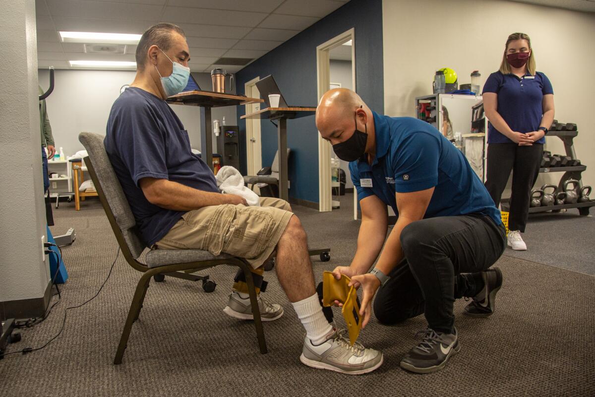 Physical therapist Andrew Duong works with David Arellano