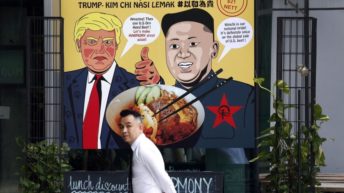 A man passes an advertisement depicting President Trump and North Korean leader Kim Jong Un, the inspiration behind a local dish, Thursday at a Singapore mall.