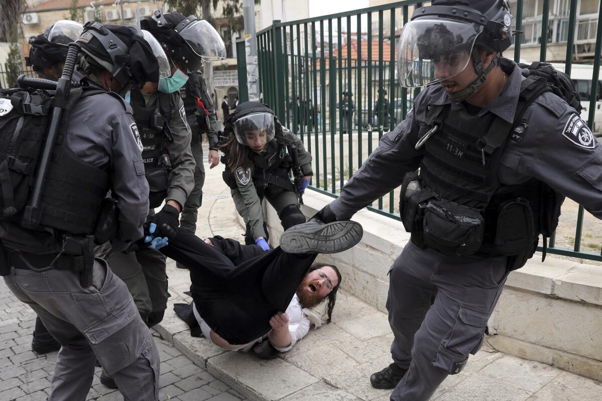 Policías arrastran a un manifestante durante una protesta contra las medidas del gobierno israelí para contener la propagación del coronavirus en un suburbio ultraortodoxo de Jerusalén el 30 de marzo del 2020. (AP Photo/Mahmoud Illean, File)