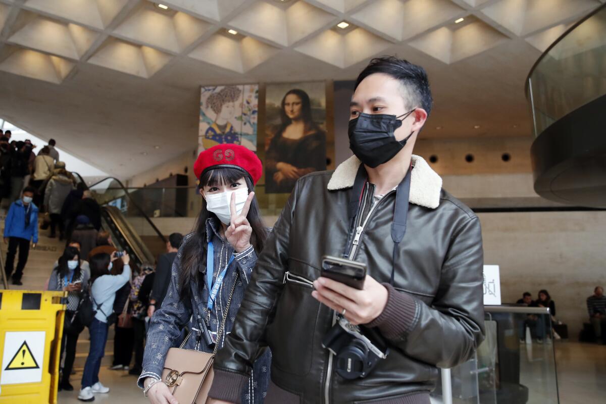 Masked tourists visit the Louvre in Paris.
