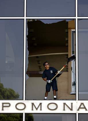 A worker removes broken glass at Pomona City Hall after a 5.4 earthquake in nearby China Hills shook the Southland, the first significant temblor in more than a decade to be centered in an urban area of California.