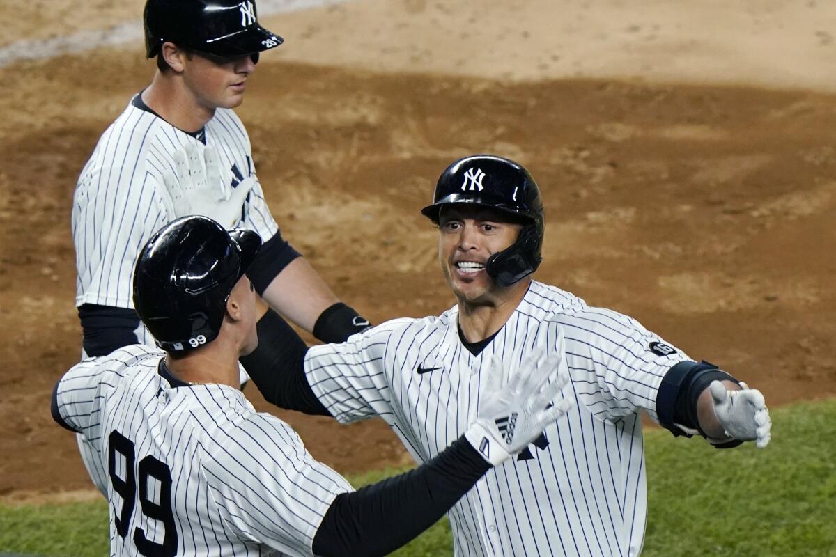 New York Yankees Aaron Judge, (99) celebrates with designated hitter Giancarlo Stanton after scoring on Stanton's fifth-inning grand slam in a baseball game against the Baltimore Orioles, Monday, April 5, 2021, at Yankee Stadium in New York. Yankees' DJ LeMahieu passes behind the pair. (AP Photo/Kathy Willens)