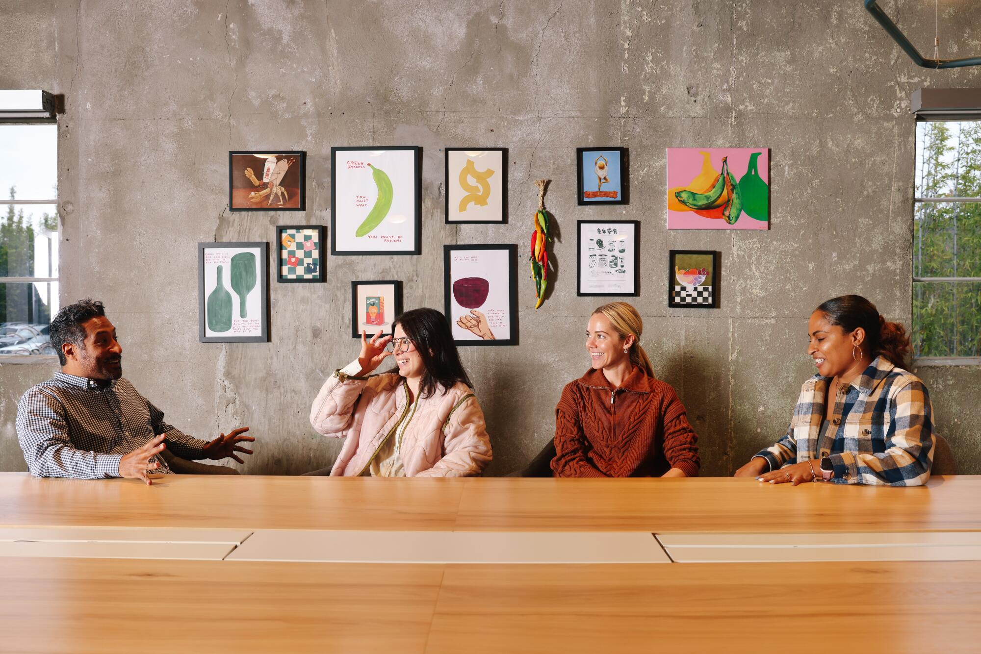 Four people seated at a conference table interact.