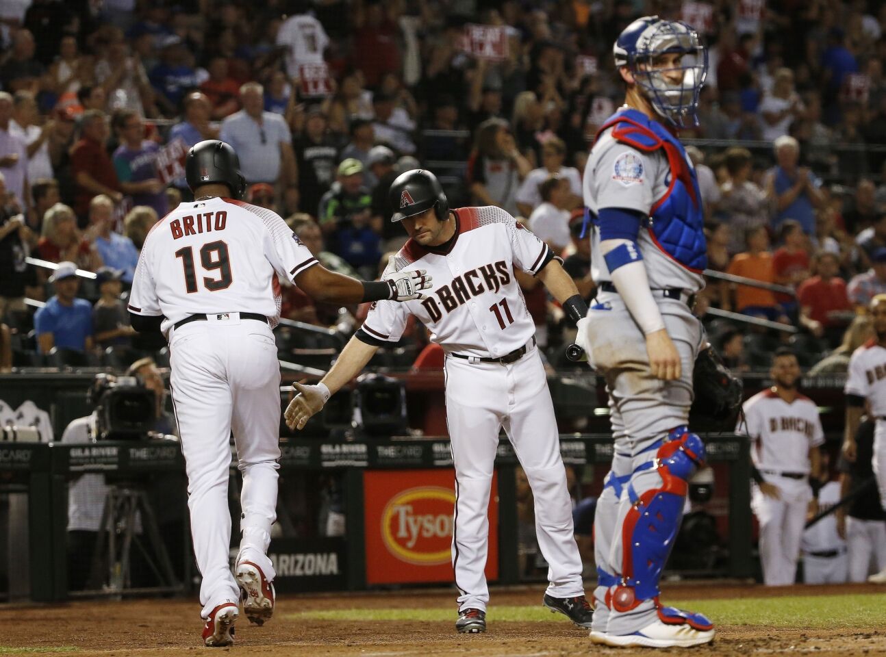 Arizona Diamondbacks' Socrates Brito (19) celebrates his home run with A.J. Pollock (11) as Los Angeles Dodgers catcher Yasmani Grandal, right, pauses at home plate during the second inning of a baseball game Wednesday, Sept. 26, 2018, in Phoenix. (AP Photo/Ross D. Franklin)