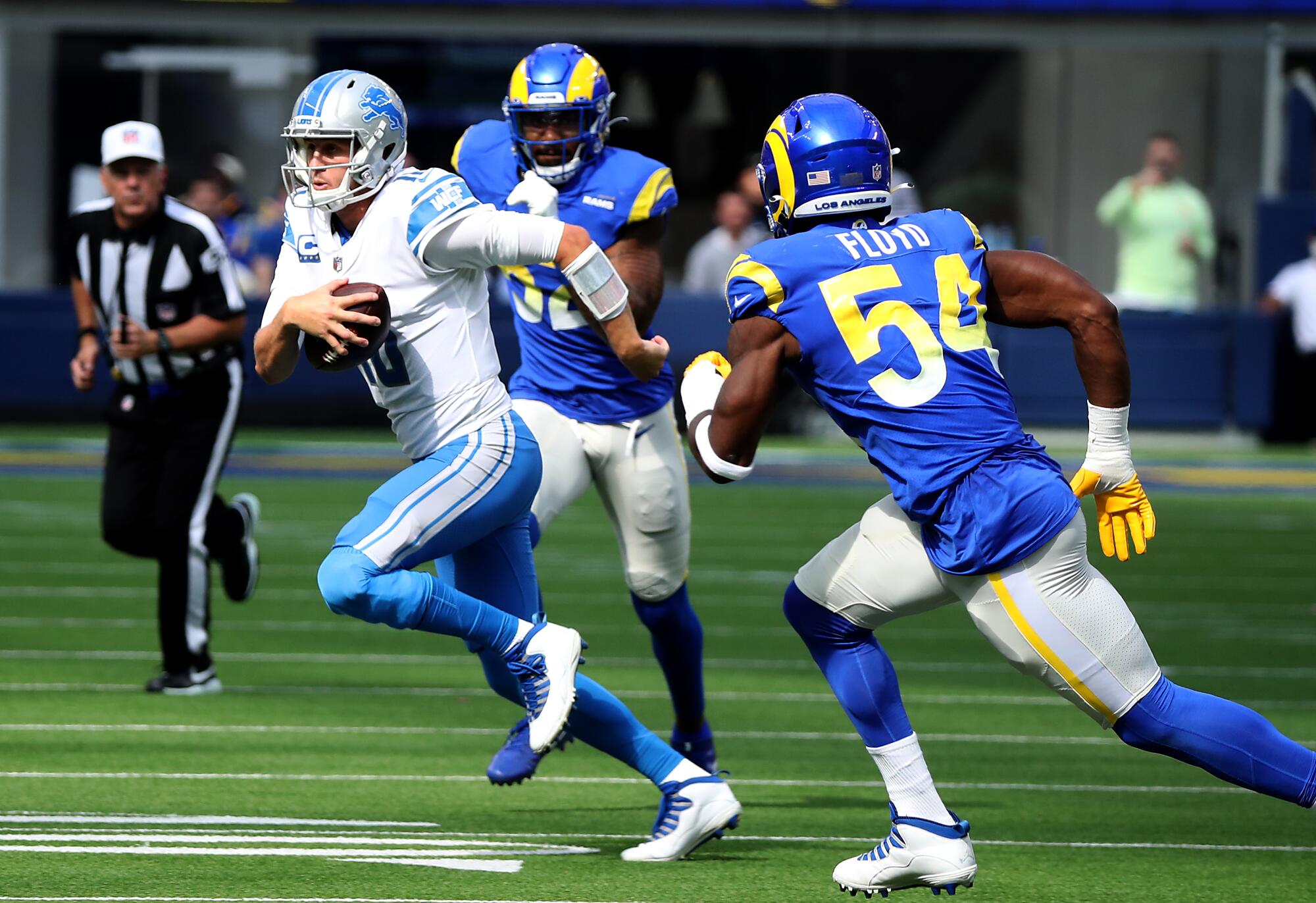 Lions quarterback Jared Goff is fluished from the pocket by Rams defenders.
